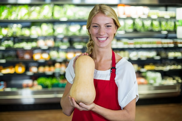 유기농 섹션에서 야채를 들고 웃는 여성 직원