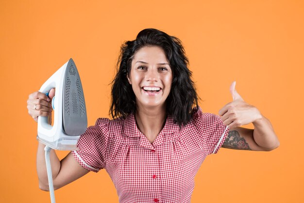 Donna sorridente con vestiti alla moda stiratura con ferro fumante vita moderna