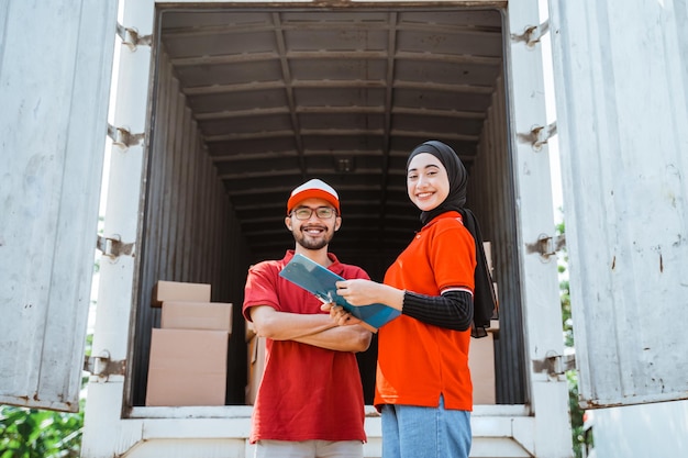 Smiling female worker holding clipboard with delivery man