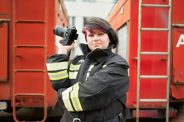 Photo smiling firefighter holding camera outdoors