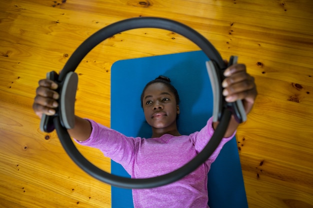 Foto donna adatta sorridente che si esercita con l'anello di pilates sulla stuoia