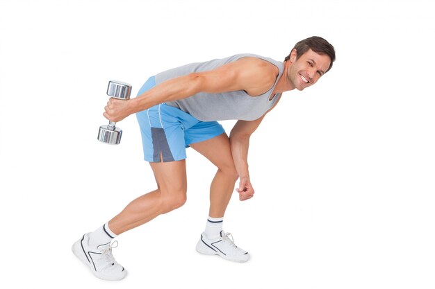 Smiling fit young man exercising with dumbbell