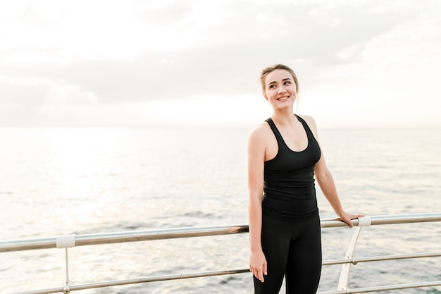 Smiling fitness woman training in the morning near the sea