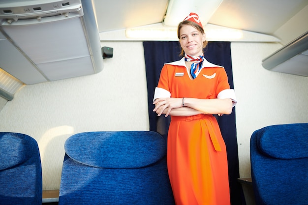 Foto assistente di volo sorridente che posa in aereo