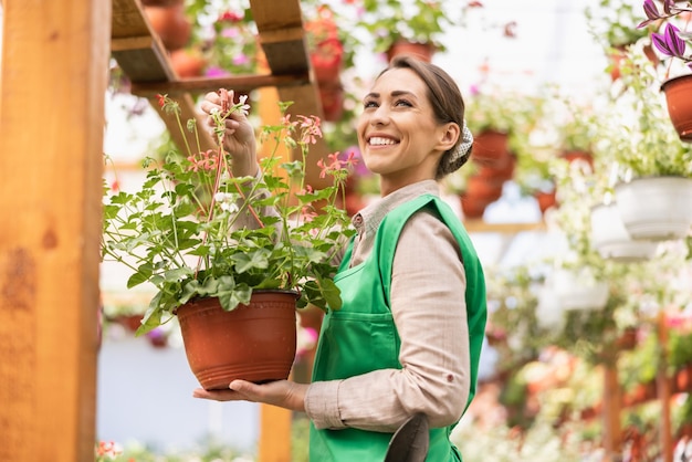Улыбающаяся женщина-флорист, работающая с цветами в садовом центре. Женщина-предприниматель.