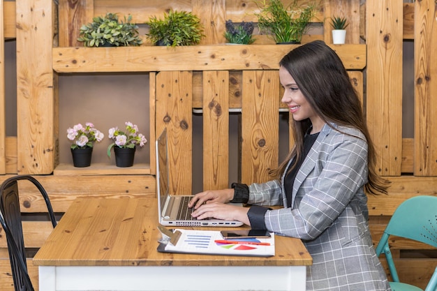 Libero professionista sorridente che lavora al computer portatile nel posto di lavoro moderno