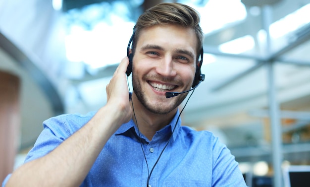 Operatore di call center maschio giovane bello sorridente amichevole.