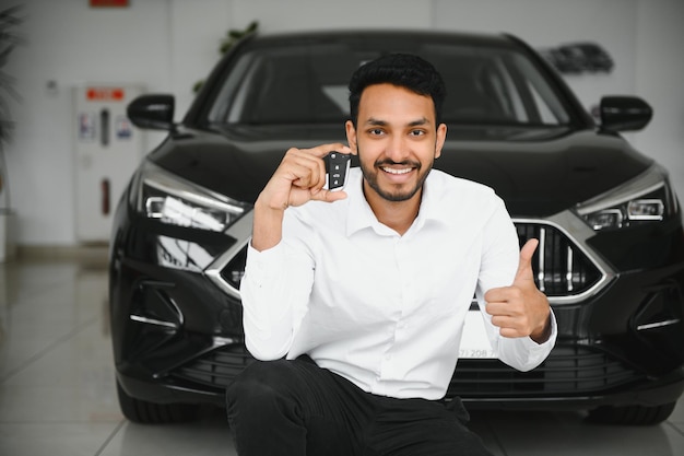 Smiling friendly indian car seller standing in car salon