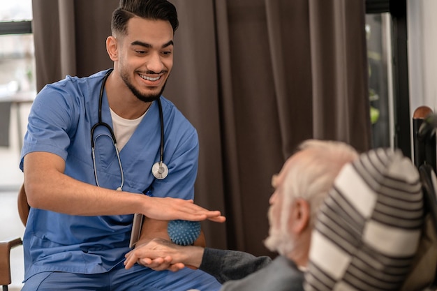 Smiling friendly physiatrist conducting an in-home physiotherapy session