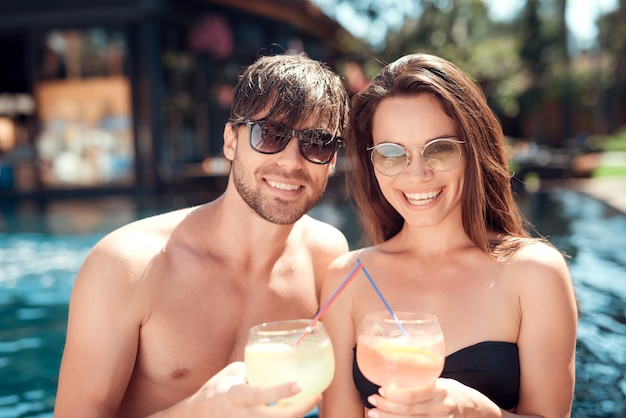 Amici sorridenti bevendo cocktail a bordo piscina