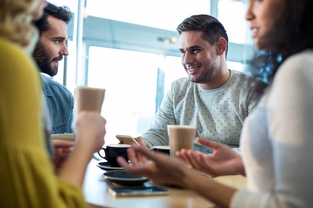 Amici sorridenti che mangiano una tazza di caffè e un caffè freddo in caffè