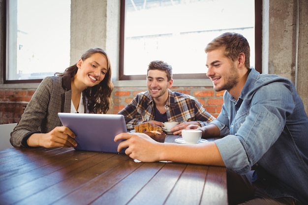 Smiling friends holding tablet and looking at it