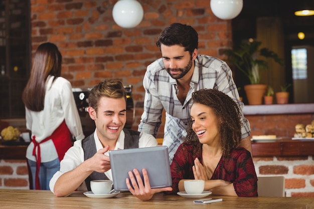 Smiling friends looking at digital tablet 