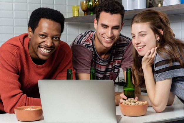 Photo smiling friends looking at laptop