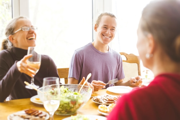 Smiling friends sit at the kitchen table. A joyful group of young people having fun together. 