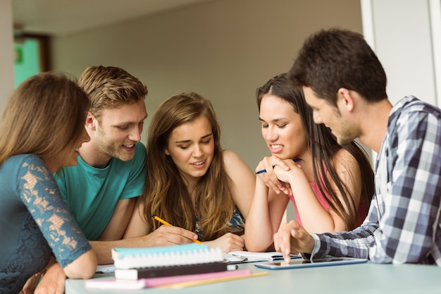 Amici sorridenti che si siedono studiando insieme