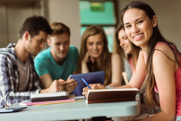 Smiling friends sitting studying and using tablet pc 