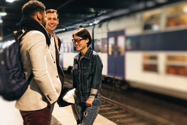 Smiling friends standing on railroad station platform