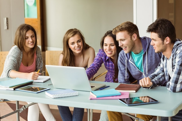 Studenti sorridenti degli amici che per mezzo del computer portatile