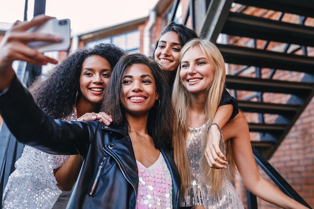smiling friends taking selfie while standing on staircase