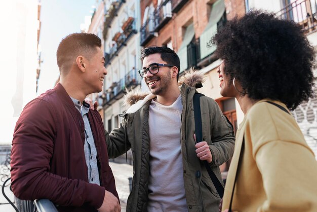 Photo smiling friends talking while standing outside building