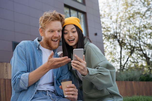 Amici sorridenti che usano il telefono cellulare guardando video che acquistano comunicazione online insieme