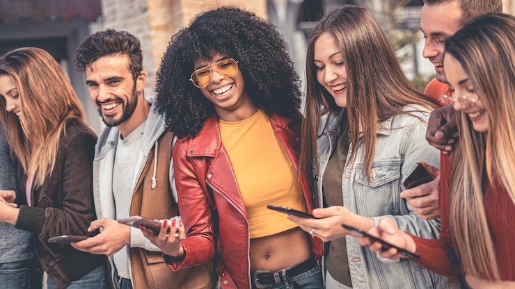 Photo smiling friends using smart phone while standing outdoors