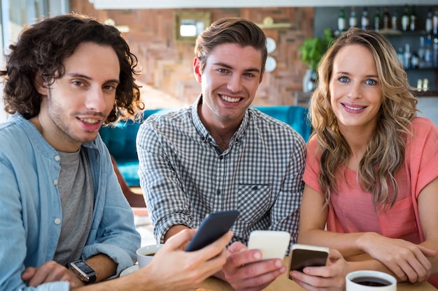 Smiling friends using their mobile phone