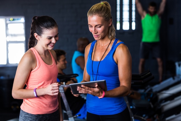 Smiling friends with digital tablet in gym