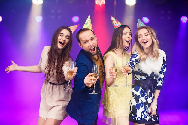 smiling friends with glasses of champagne in club