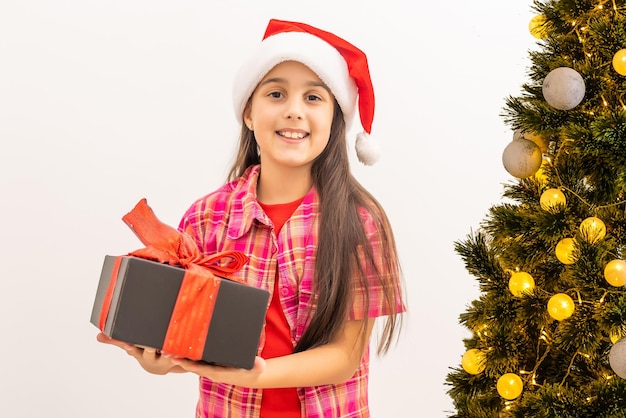 Smiling funny child in Santa red hat. Holding Christmas gift in hand. Christmas concept. on white background.