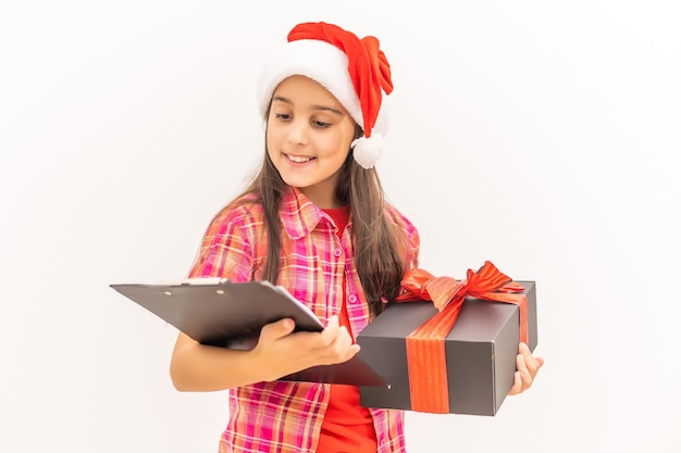 Smiling funny child in Santa red hat. Holding Christmas gift in hand. Christmas concept. on white background