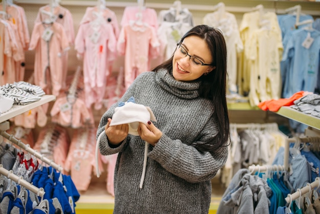 Smiling future mother chooses baby hat