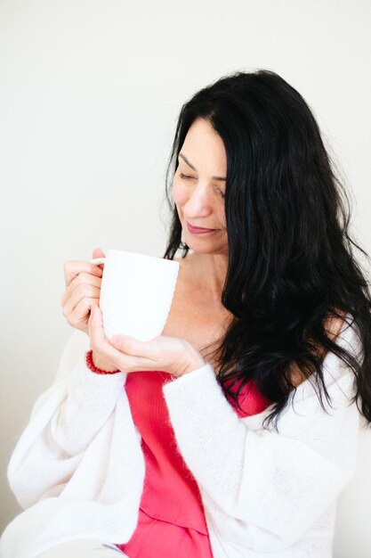 Smiling gently this woman holding a coffee cup symbolizes finding balance and comfort during menopause and overcoming hormonal and emotional difficulties and crisis