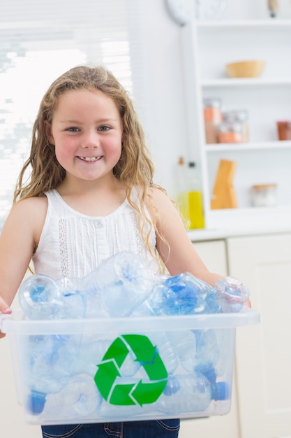 Smiling girl carrying box of the bottles