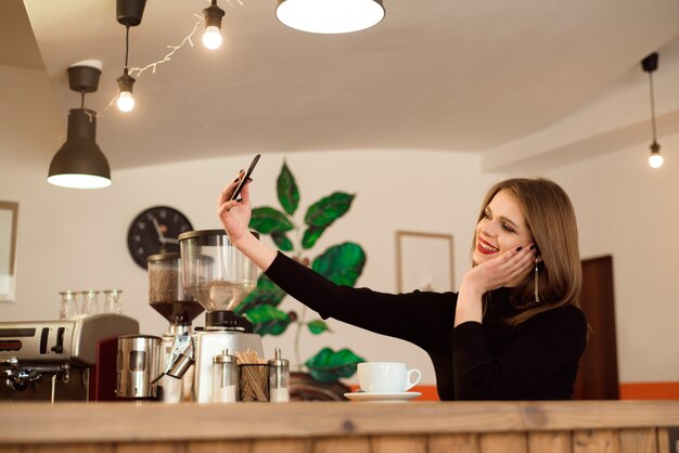 Smiling girl in a coffee shop with a phone.