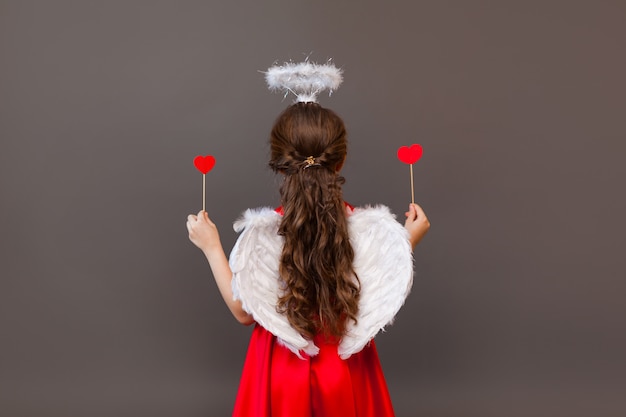 Smiling girl Cupid angel, with heart-shaped lollipop