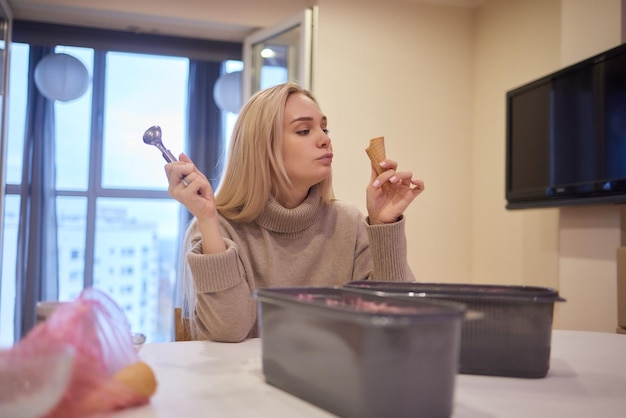 Ragazza sorridente che mangia un gelato mani mettendo le palline di gelato nel cono di cialda