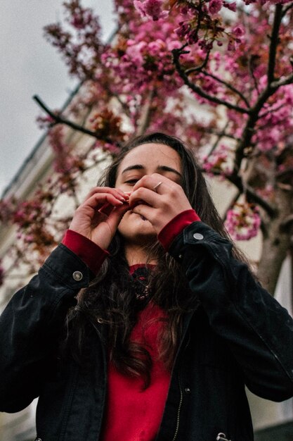 Ragazza sorridente che gode degli alberi primaverili dell'infiorescenza