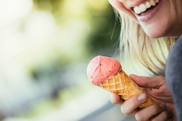 Foto la ragazza sorridente gode del suo gelato alla fragola durante una giornata estiva