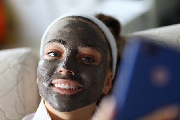 Foto la ragazza sorridente ha la maschera di carbone nera sul viso