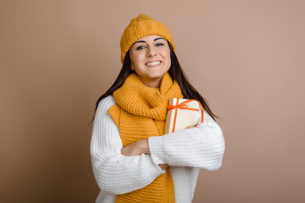 Smiling girl in hat and scarf holds a gift in her hands