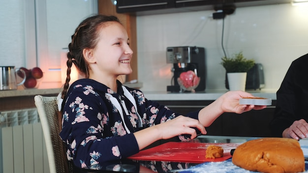 smiling girl helping her mom to make gingerbread cookies