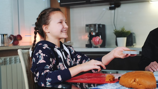 Smiling girl helping her mom to make gingerbread cookies