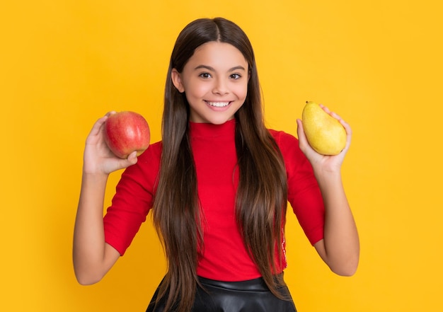 Smiling girl hold fresh apple and pear on yellow background