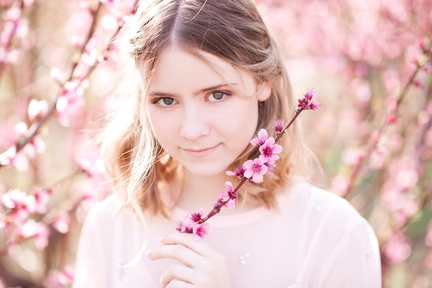 桃の果樹園で花を保持している笑顔の女の子