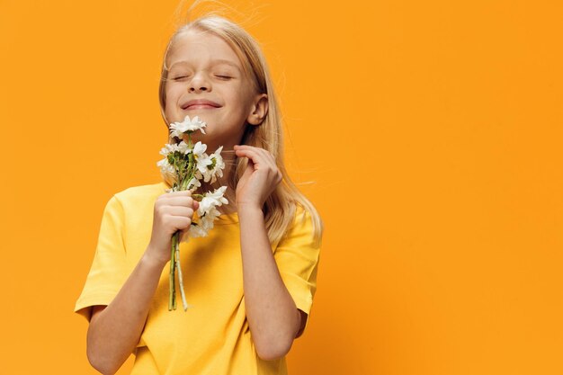 Smiling girl holding flowers standing against yellow background