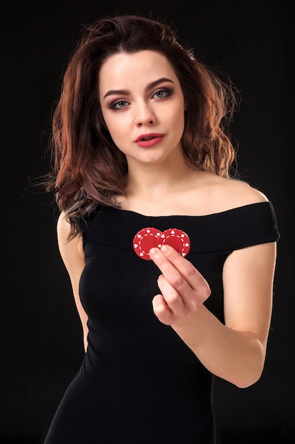 Smiling girl holding a gambling chips in her hands on black background.