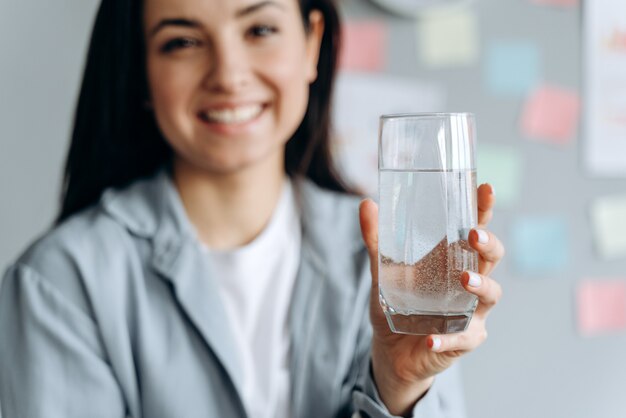 Улыбающаяся девочка держит стакан воды