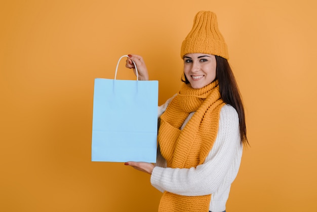 Smiling girl holding a paper bag in her hand. On an orange background